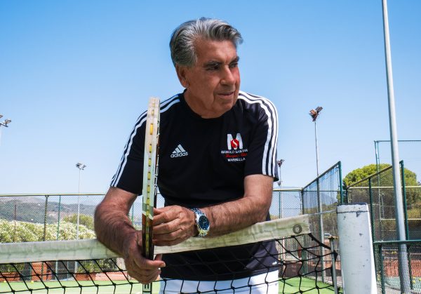 Entrevista a Manolo Santana Hombre mayor apoyado sobre la red de tenis