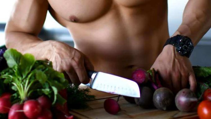 Hombre sin camisa cortando verduras Tips de nutrición para la construcción muscular