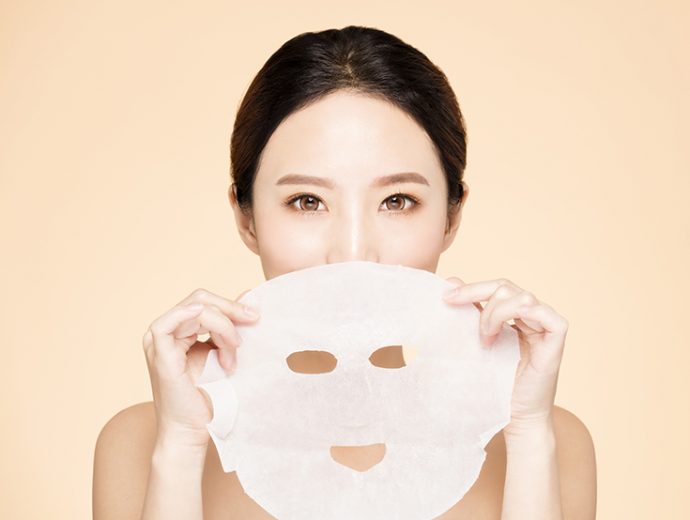 K-beauty, mascarillas coreanas mujer coreana sosteniendo una mascarilla coreana