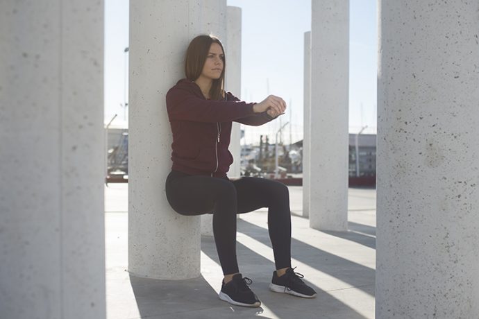 Mujer practicando as sentadillas apoyada a la pared